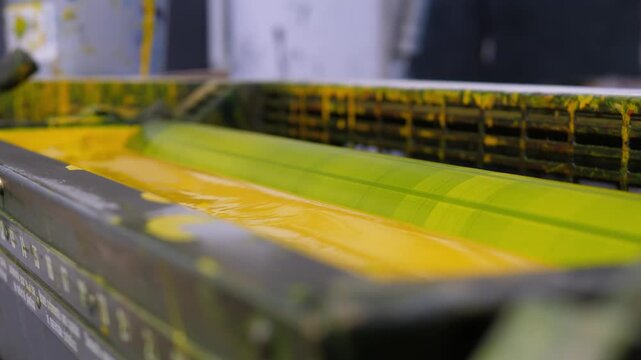 Yellow ink unit operating inside an offset industrial printing press
