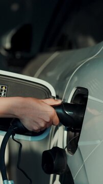 4K slow motion person charging electric car at home.	
