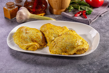 Raw chicken thighs marinated in yellow curry spice with fresh herbs and vegetables © Andrei Starostin