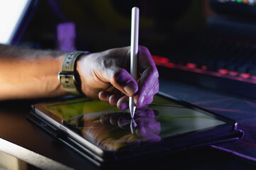 Left-handed digital artist drawing on tablet with stylus under creative neon lighting