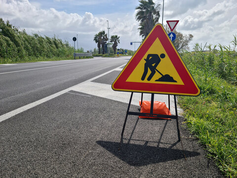 Road works warning sign on highway roadside, traffic regulation and transportation safety concept, temporary construction zone and driving restriction information.