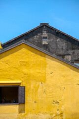 Obraz premium Minimal yellow wall and geometric rooftop under blue sky in Hoi An Vietnam