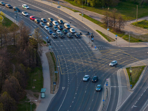 Aerial view of a busy road intersection with cars waiting at traffic lights and yellow box junction markings in Vilnius County, Lithuania.