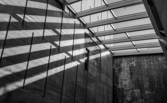 The interior of a concrete brutalist style building with strong light and shadows, nobody