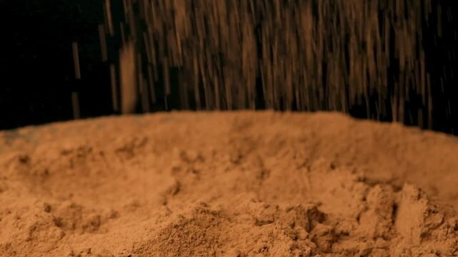 Cinematic sprinkle of raw cocoa powder on black background slow motion