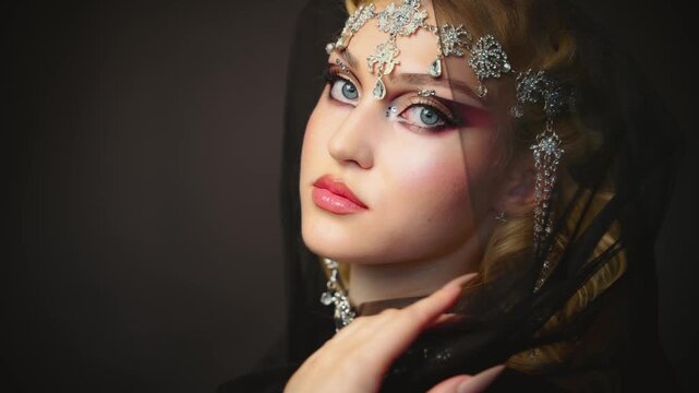 Fantasy girl portrait dark queen woman beautiful face with art creative graphic make-up blue green eyes, luxury elf girl, black veil hood on head blonde long hair silver jewelry tiara crown diamonds.