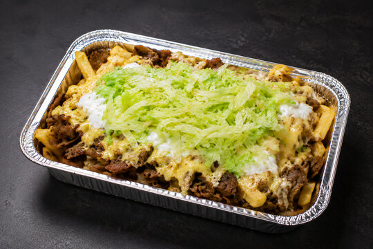 Cinematic Dutch kapsalon kebab fries in aluminum tray on dark studio table
