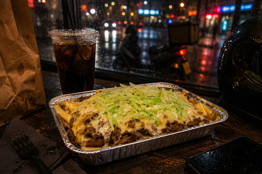 Dutch kapsalon takeaway meal in rainy urban delivery night scene