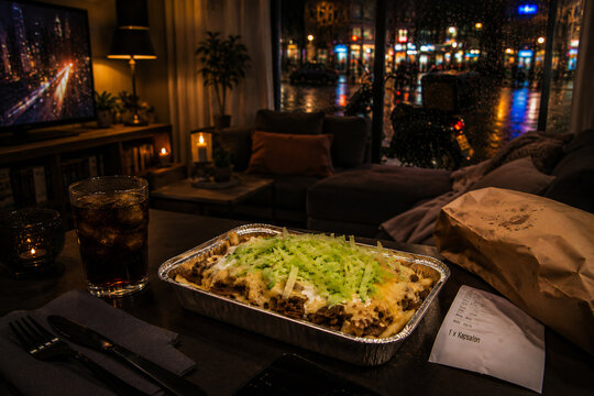 Dutch kapsalon takeaway meal in rainy urban delivery night scene