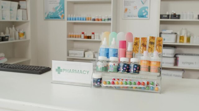 Detail shot of pharmacy interior with Pharmacy sign on white checkout counter and medication bottles for sale on shelves in background, no people, copy space