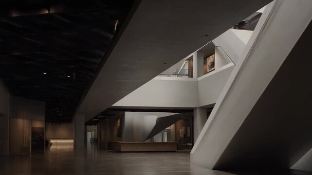 Contemporary museum lobby featuring a minimalist design concrete structure, creating geometric shadows and patterns in the expansive interior space with subtle lighting