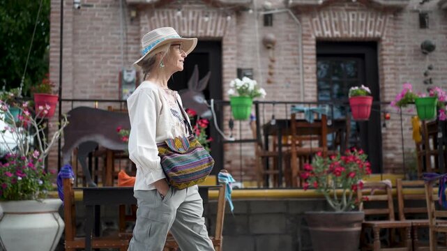 Mature woman explores the mission in San Ignacio, Baja California Sur, walking past colorful buildings and enjoying the local culture