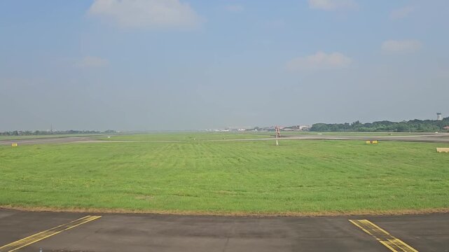 An expansive aerial view captures a commercial aircraft taking off from Soekarno-Hatta International Airport, revealing the massive GMF AeroAsia maintenance hangars, taxiways, and parked airplanes.