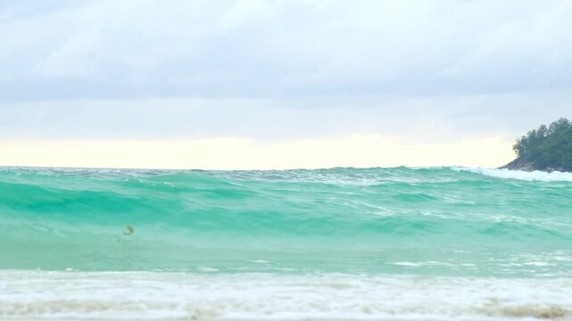 Soft surf rolls toward the tropical shoreline as light waves break across wet beach sand. The clip captures natural ocean rhythm, useful for coastal scenery visuals, tourism marketing, or tranquil