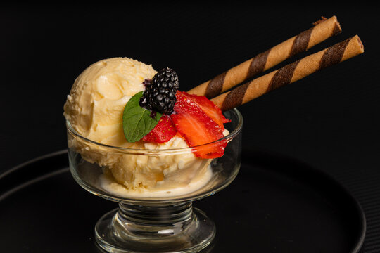 Helado de vainilla con fresas, ar&aacute;ndanos y galleta en tubo servida en copa