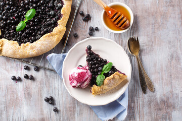 Rustic berry crispy blueberry pie with ice cream and mint on white wooden table, top view © Iuliia Metkalova