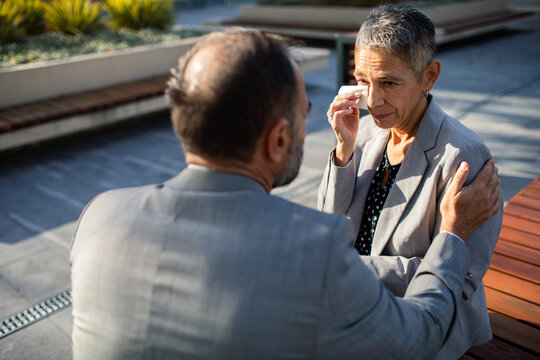 Colleague comforting crying senior businesswoman at office plaza