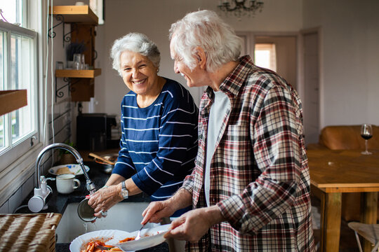 Senior couple washing dishes together in home kitchen