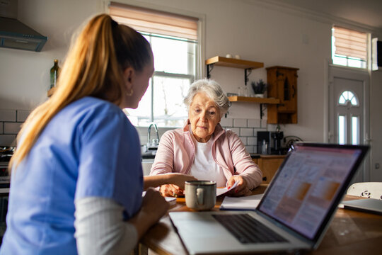 Nurse helps senior woman review paperwork at home