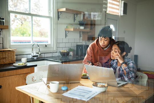 Two women reviewing finances at home kitchen table