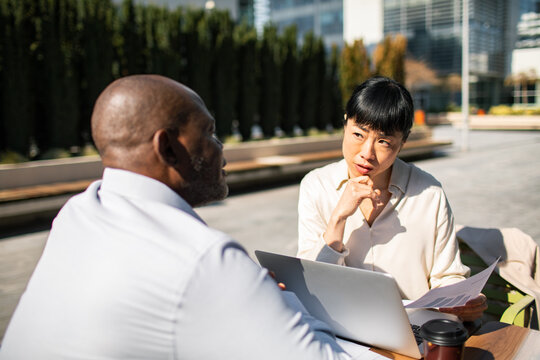 Two business colleagues discussing strategy outdoors in city plaza