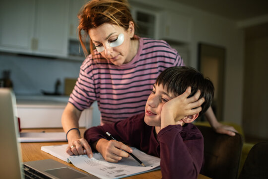 Parent helping child with homework at kitchen table