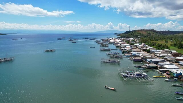 Aerial drone footage of Labuan Jambu village coastline, with fishermen houses and fishing wooden boats, blue waters, a place to watch whale sharks, in Sumbawa regency, Sumbawa island, Indonesia 