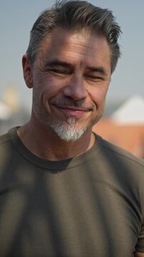 Portrait of happy casual older bearded man outdoor, smiling, Mid adult, mature age guy in 50s standing on balcony or terrace.