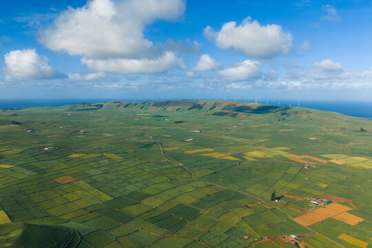 Aerial view of Pico Dona Joana geodesico overlooking a patchwork of green fields and wind turbines under a cloudy sky Feteira, Acores, Portugal.