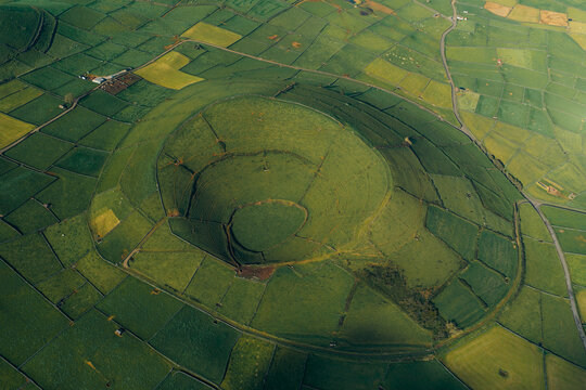 Aerial view of the Pico Dona Joana geodesico volcanic crater surrounded by a patchwork of green fields and stone walls in Feteira, Acores, Portugal.