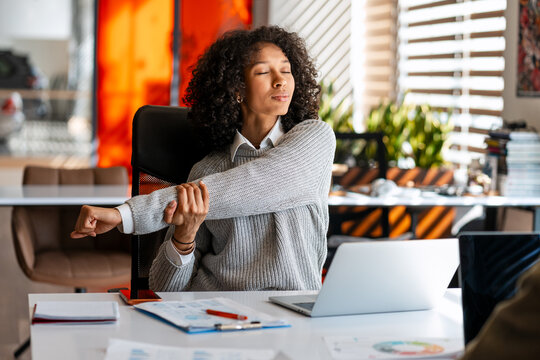 Young woman stretching arm enjoying a wellness break in office
