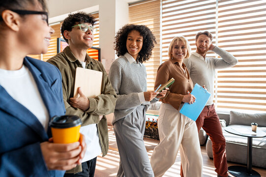 Diverse business team collaborating smiling walking through office
