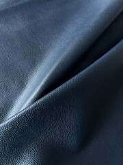 Fototapeta premium Dark navy blue leather texture with elegant folds and fine grain detail, featuring premium luxury material, smooth abstract surface and modern minimalist aesthetic in close-up composition.
