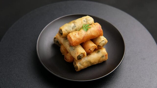 egg rolls,Deep fried Chinese Chives Spring Rolls(Gui Chai) and Glass noodle spring rolls on a black plate.Thai snack food.