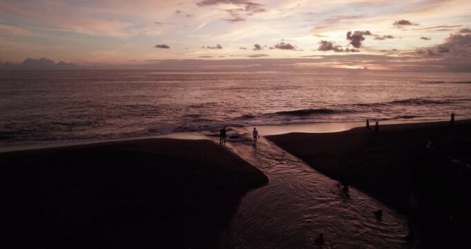 Drone shot of sunset in Bali. The river flows into the Pacific Ocean. People are having fun and having a nice time