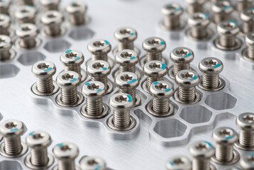 Obraz premium Screws are placed in a hexagonal pattern on a metal tray. The screws are silver and have colored markings. This scene shows a part of a production or assembly process in a factory.