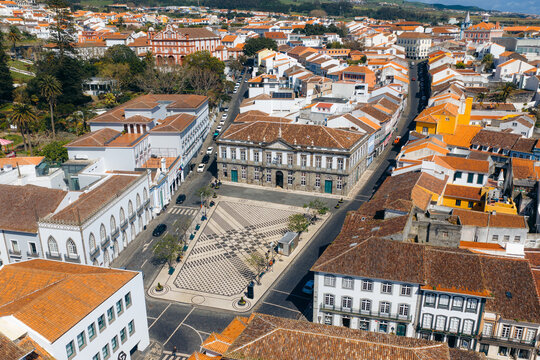 Aerial view of Praca Velha with its patterned pavement and the historic Town Hall building surrounded by traditional houses in Angra do Heroismo, Azores, Portugal.