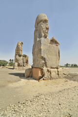 Fototapeta premium The Colossi of Memnon two massive stone statues of the Pharaoh Amenhotep III, which stand at the front of the ruined Mortuary Temple of Amenhotep III