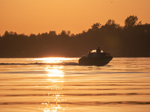 Motor boat on lake or river at sunset background
