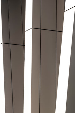 vertical panels divide geometric architecture beside a pale facade, where shadow, exterior cladding and urban structure become the abstract subject.