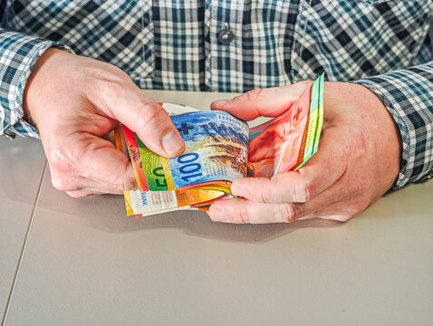 Close up of male hands holding fan of Swiss Franc banknotes CHF currency for savings and investment