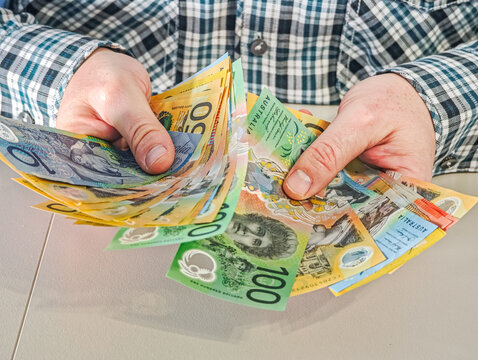 Businessman holding variety of Australian dollar banknotes 100, 50, 10 AUD for financial concept