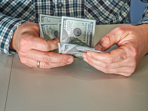 Businessman counting one hundred US dollar banknotes, hands holding stack of USD cash money