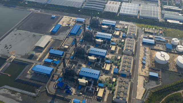 Aerial view of the Gulf Pluak Daeng Power Plant GPD featuring blue industrial buildings, tall smokestacks, and circular storage tanks in Map Yang Phon, Rayong, Thailand.