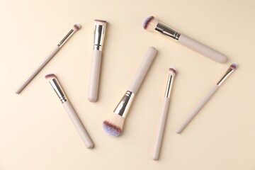 Fototapeta premium Many clean makeup brushes on beige background, flat lay