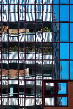 blue glass facade frames office windows and reflection patterns across urban architecture, with grid exterior details crossing mirrored vertical lines