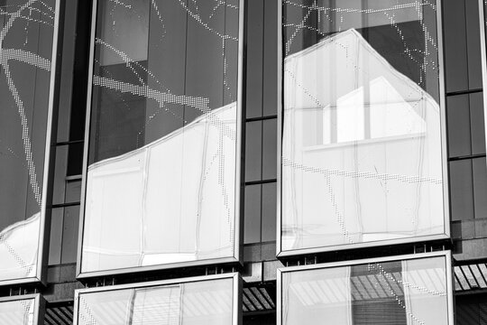 glass facade reflection moves through windows in a monochrome composition, turning urban architecture exterior panels into a quiet geometric pattern