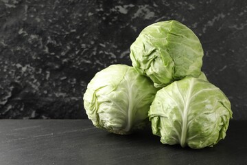 Fototapeta premium Fresh cabbages on black textured table, closeup. Space for text