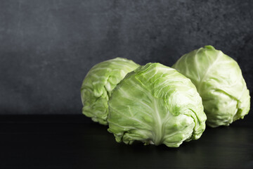 Fototapeta premium Fresh ripe cabbages on black wooden table, closeup. Space for text