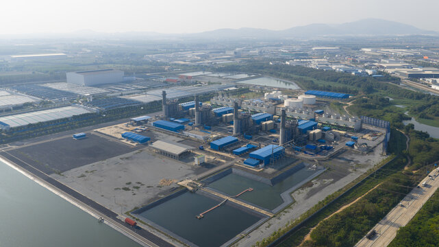 Aerial view of the Gulf Pluak Daeng Power Plant featuring blue industrial buildings, tall smokestacks, and water reservoirs in Map Yang Phon, Rayong, Thailand.